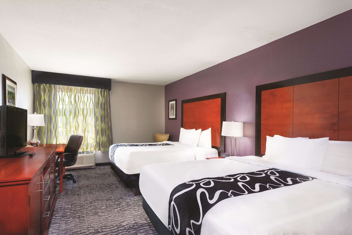 Une chambre d’hôtel avec deux lits, un bureau et une chaise.