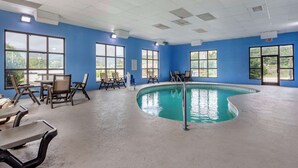Una piscina interior amb parets blaves i grans finestres, envoltada d'espais d'estar i un sostre amb il·luminació empotrada.