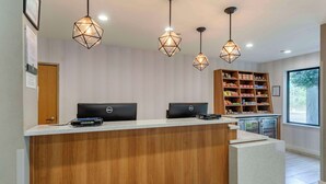 Una recepció amb dos ordinadors Dell, un taulell de fusta i una vitrina de vidre.