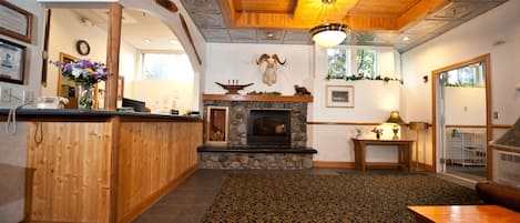 A cozy interior with a stone fireplace, wooden paneling, and a patterned carpet.