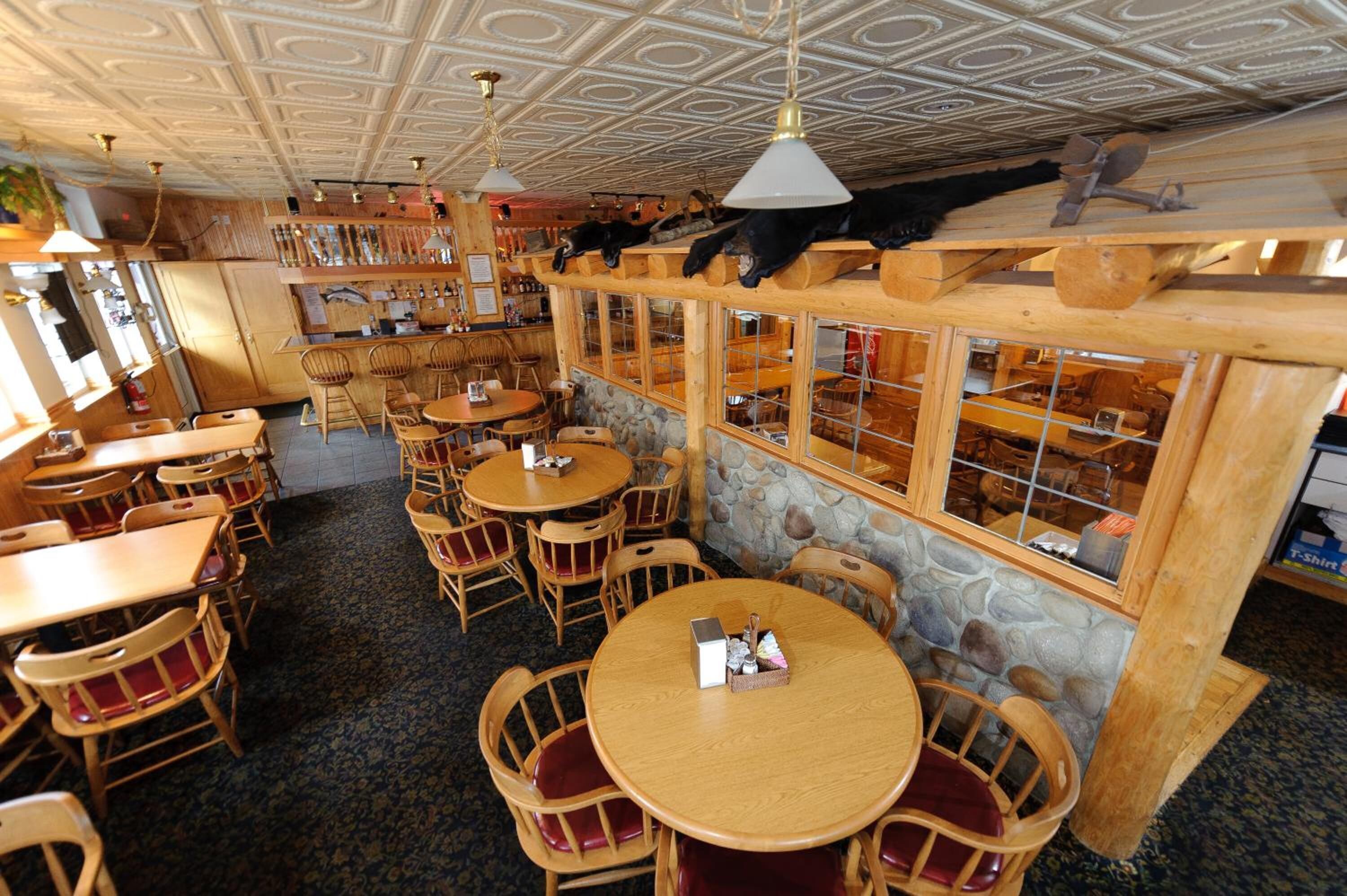 Un restaurante acogedor con muebles de madera, paredes de piedra y un techo con un diseño geométrico.