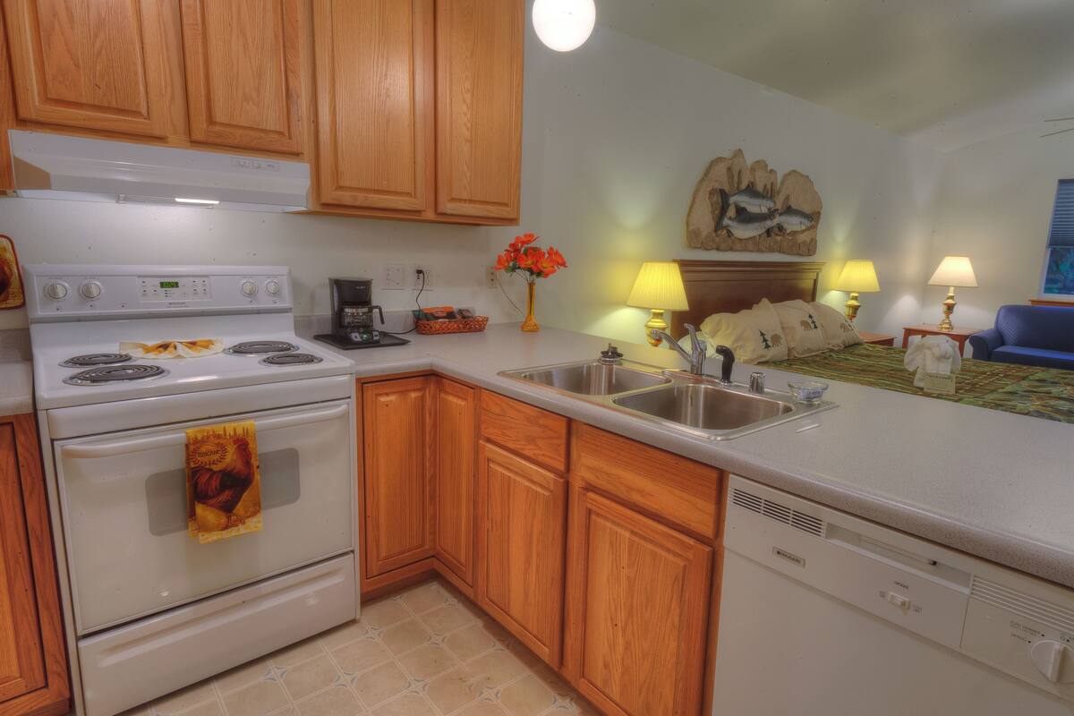 A kitchen with wooden cabinets, a white stove, and a sink.