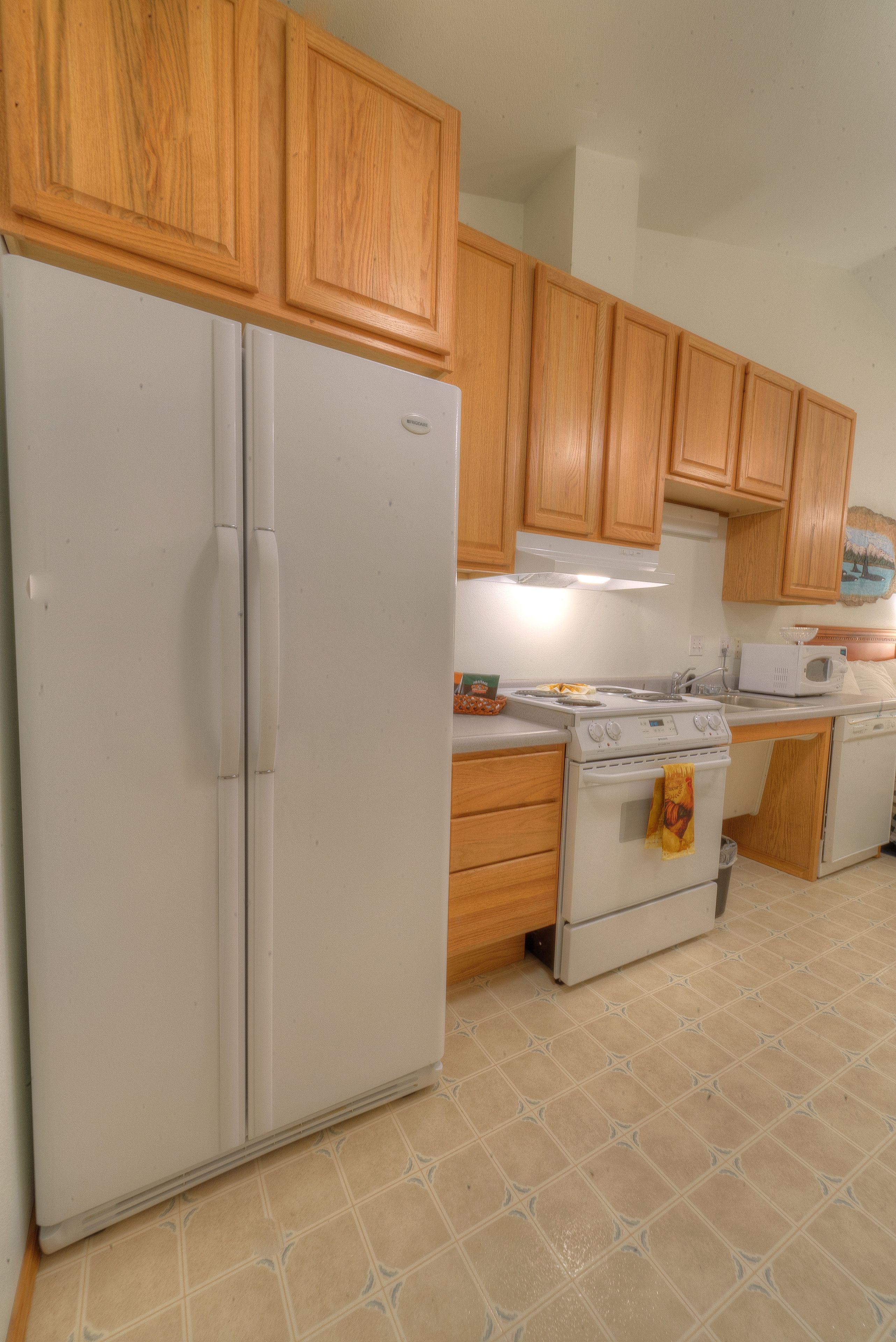 A kitchen with wooden cabinets, a white refrigerator, a stove, and a microwave.