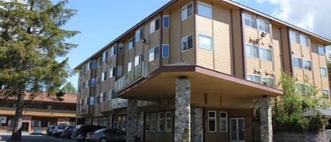 A multi-story hotel with a flat roof and a covered entrance area supported by stone pillars.