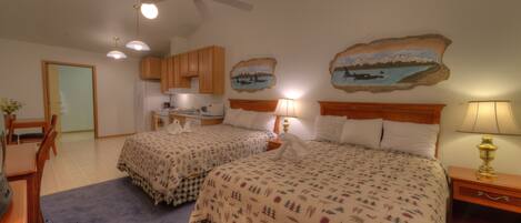 Ein Schlafzimmer mit zwei Betten, einem Deckenventilator und einer Küchenzeile im Hintergrund.