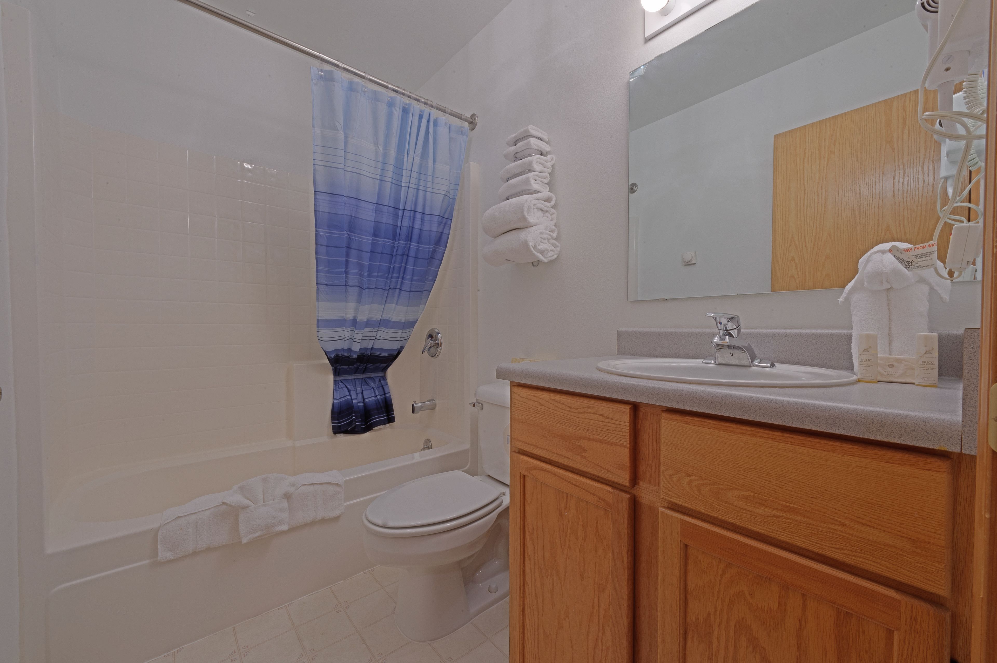 A bathroom with a bathtub, toilet, sink, and wooden cabinets.