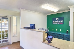 Een receptie met een balie, een computer, een printer en een bordje voor HomeTown Studios by RedRoof.