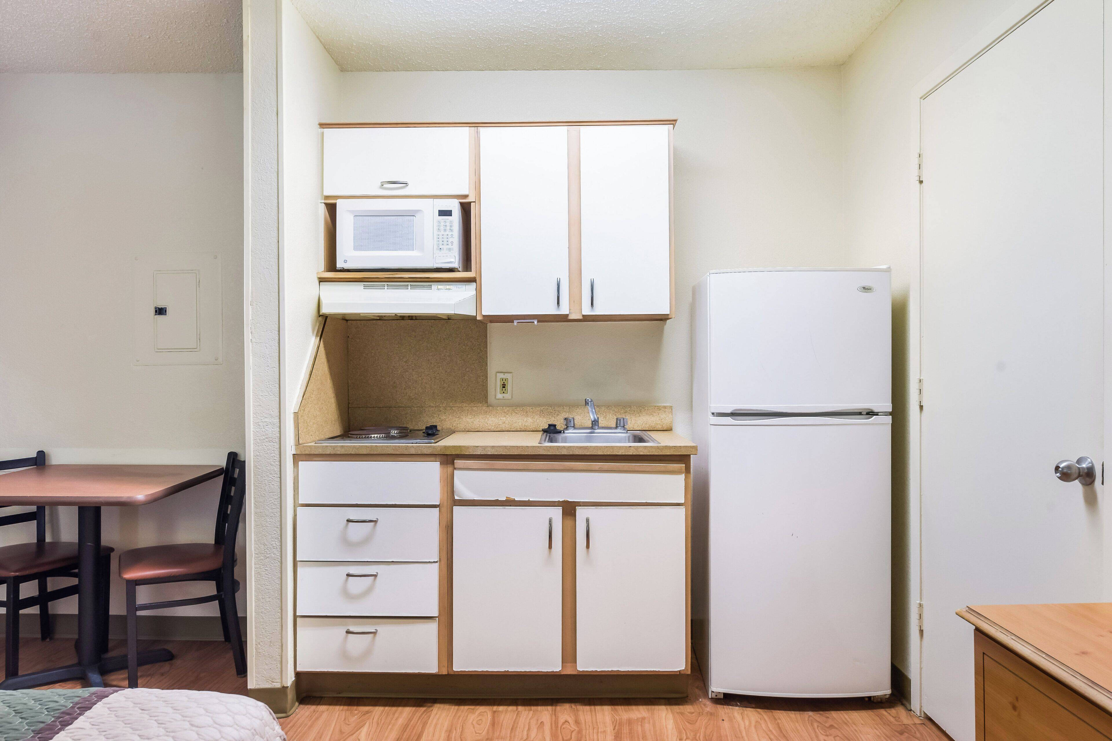 A compact kitchen with a microwave, refrigerator, and a small sink.