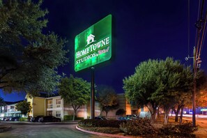 A nighttime view of a building with a sign that reads 'HOME TOWNE STUDIOS by Red Roof.' - HomeTowne Studios By Red Roof Dallas - North Addison/ Tollway (Dallas)