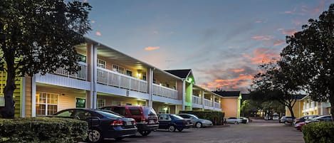 A hotel with multiple floors, outdoor parking, and a clear sky.
