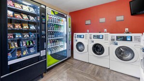 A laundry facility with multiple washing machines and a vending machine with snacks and drinks. - Extended Stay America Suites San Diego Fashion Valley (San Diego)