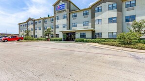A multi-story hotel with a prominent 'Now Open' sign, a parking lot, and a Walmart store in the background. - Studio 6 Killeen, TX (Killeen)