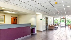 A reception area with a counter, seating area, and exit sign. - Studio 6 Killeen, TX (Killeen)