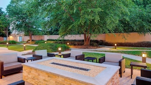Un patio al aire libre con una fogata, asientos e iluminación ambiental.