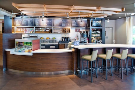 A modern bar area with a wooden counter, bar stools, and a menu board.