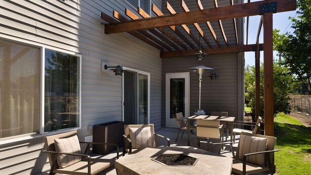 An outdoor patio with a stone fire pit, wicker furniture, and a pergola structure. - Country Inn & Suites by Radisson, Portland International Airport, OR (Portland)