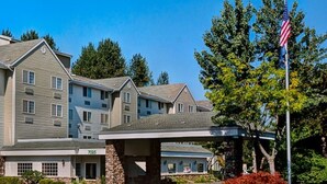 A large, multi-story hotel with a covered entrance and an American flag. - Country Inn & Suites by Radisson, Portland International Airport, OR (Portland)