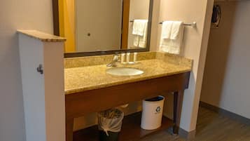 A bathroom with a granite countertop sink, a mirror, a towel rack, and a trash can.