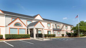 A multi-story hotel with a symmetrical facade, large windows, and a flagpole. - Microtel Inn & Suites by Wyndham Columbia/Fort Jackson N (Columbia)