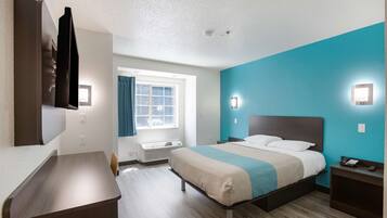 A hotel room with a bed, bedside table, and a desk.