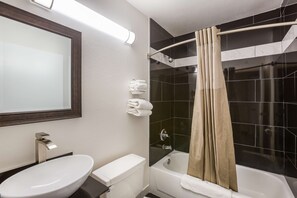 A bathroom with a white sink, toilet, and bathtub, a mirror, and a shower curtain. - Motel 6 Smyrna, GA - Atlanta (Mableton)