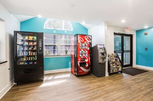 Un área de venta automática con una máquina de Coca-Cola, una máquina expendedora de aperitivos y un cajero automático.