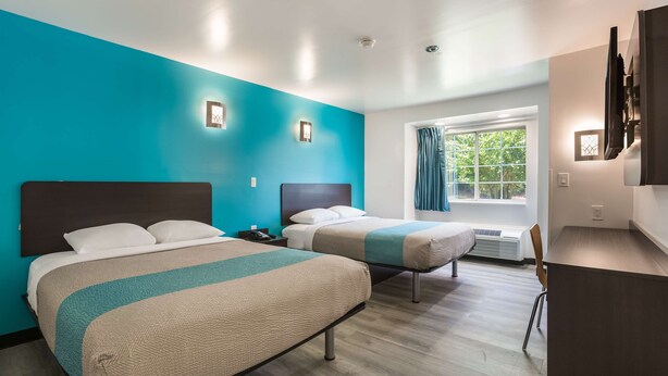 Ein Hotelzimmer mit zwei Betten, einem Schreibtisch und einem fenster mit Vorhängen.