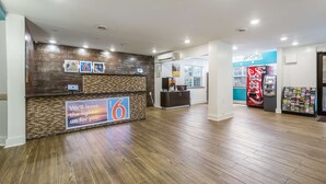 Ein Hotel-Empfangsbereich mit Holzbude, einem digitalen Bildschirm und einem Verkaufsautomaten.