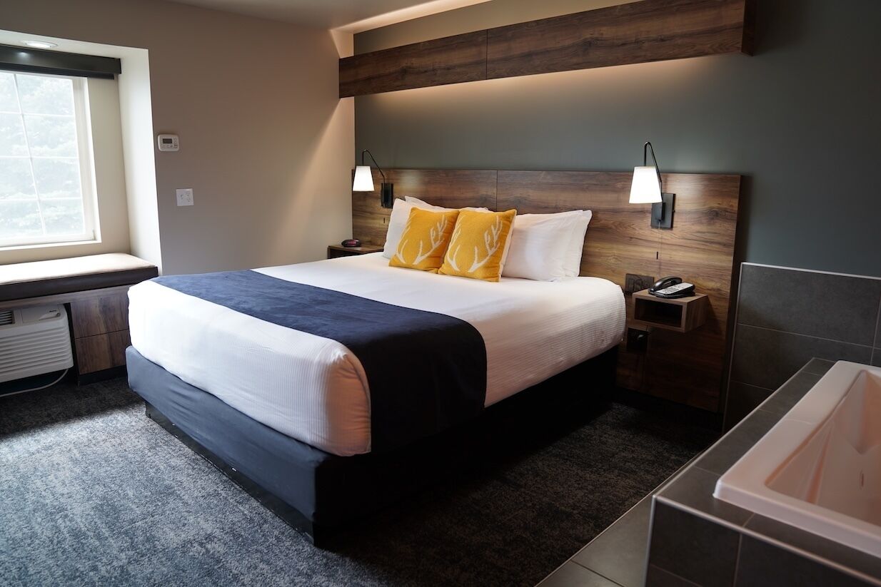 Una habitación de hotel moderna con una cama grande, lámparas de noche, un calentador integrado y una bañera.