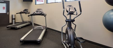 A gym with treadmills, an elliptical, and exercise balls.