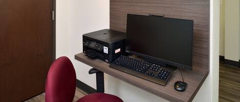 Un espacio de trabajo funcional con escritorio, monitor de ordenador, teclado, ratón e impresora.