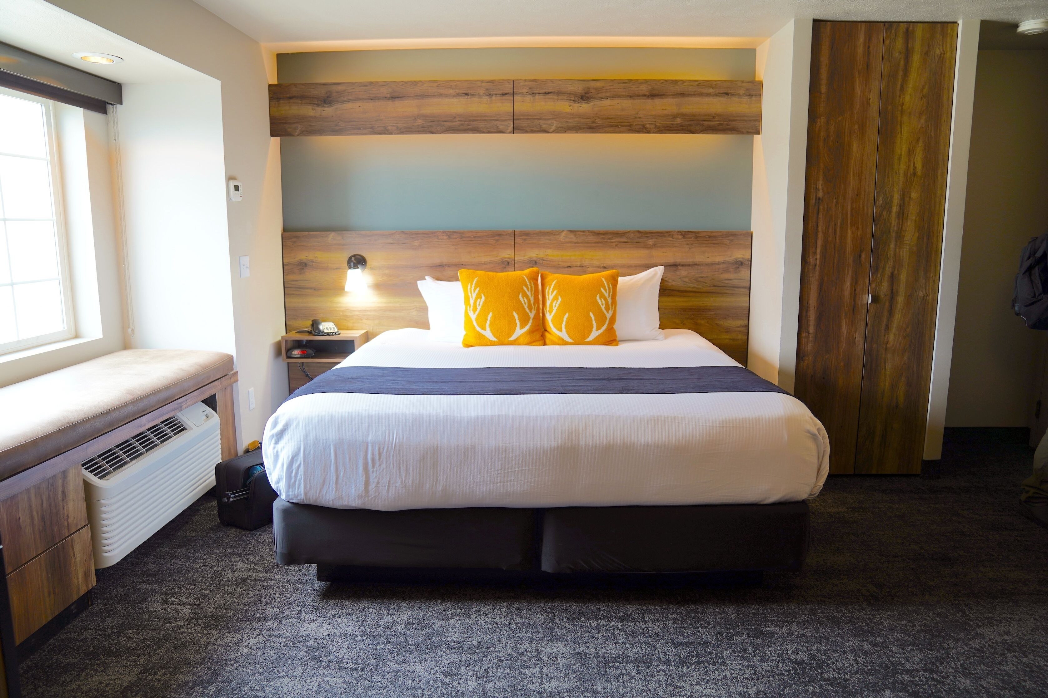 A hotel room with a large bed, a bench, a nightstand, and a wardrobe.