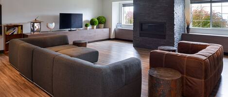 A modern living room with a large sectional sofa, a fireplace, and a television on a wall.