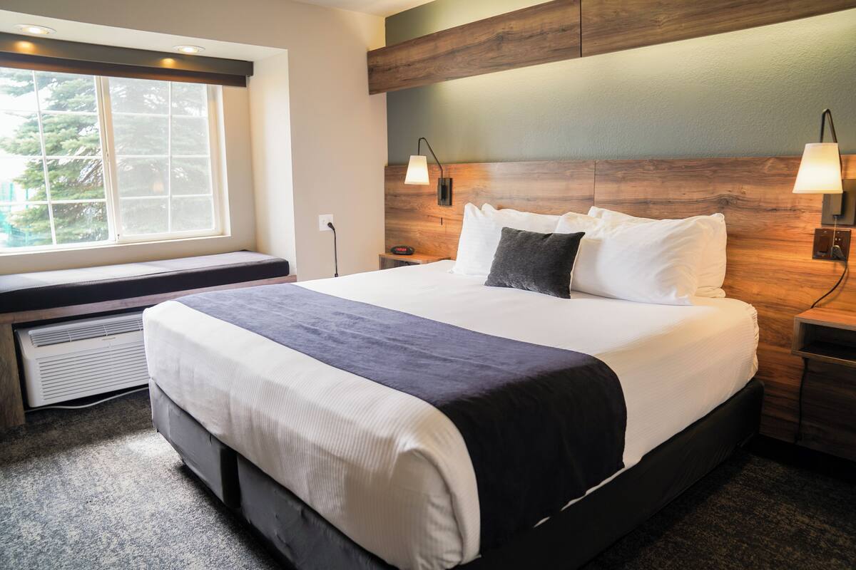 Una habitación de hotel moderna con una cama grande, un banco junto a la ventana y un calefactor integrado.