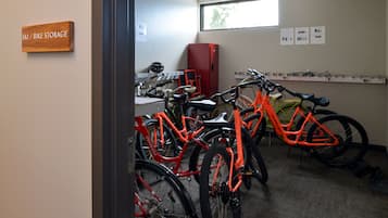 Un espace de stockage pour vélos contenant plusieurs vélos, un placard rouge et un panneau indiquant l’emplacement du stockage.