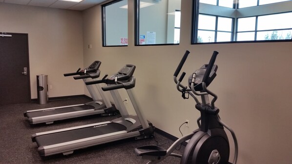 A fitness room with treadmills and an elliptical machine.