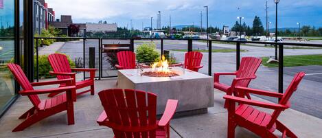 Eine Terrasse mit roten Adirondack-Stühlen und einem Feuerkorb.