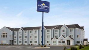 Un bâtiment de la chaîne Microtel Inn & Suites by Wyndham, avec une façade bleue, de nombreuses fenêtres et un parking situé à l’avant.
