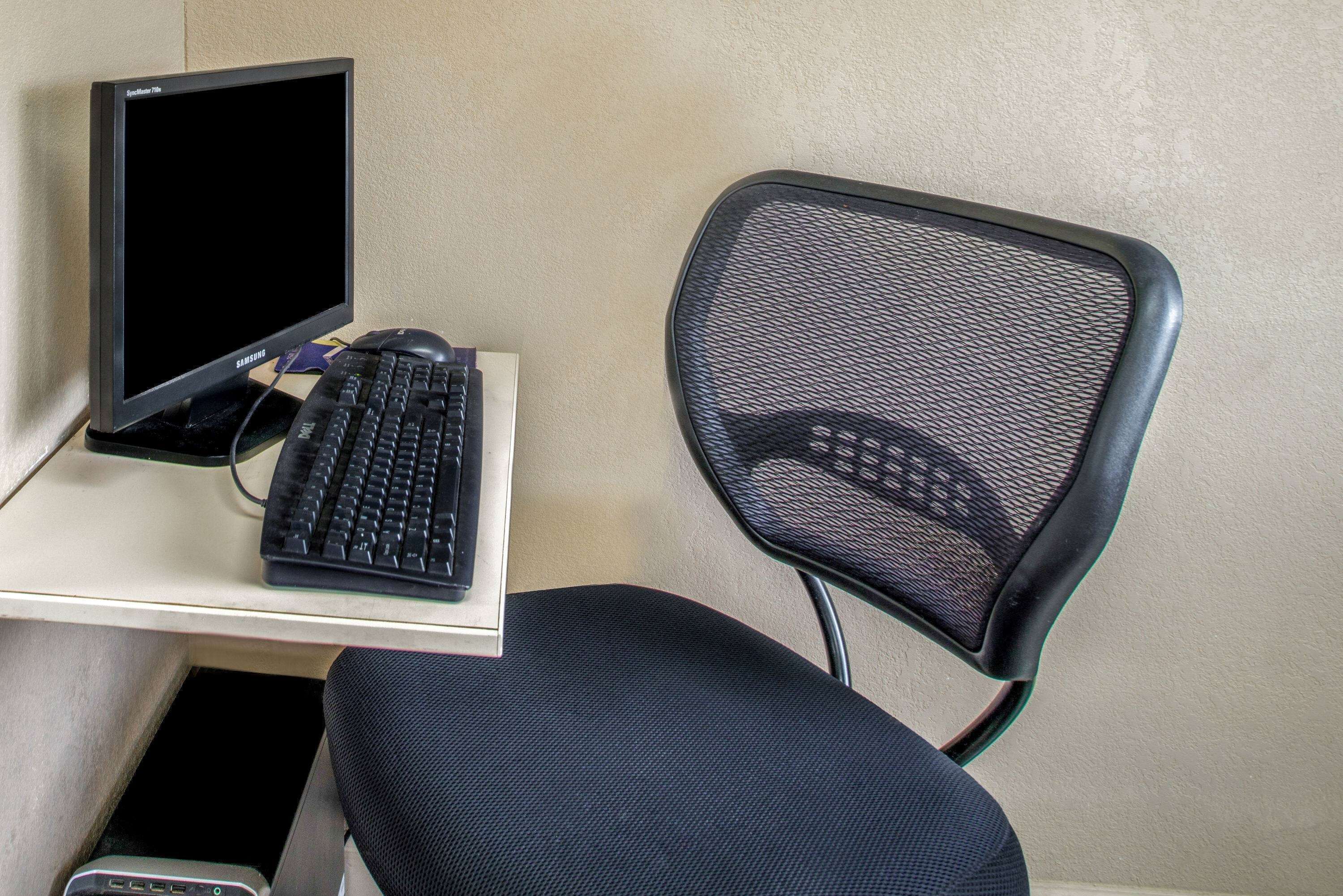 A computer setup with a monitor, keyboard, and chair on a desk.