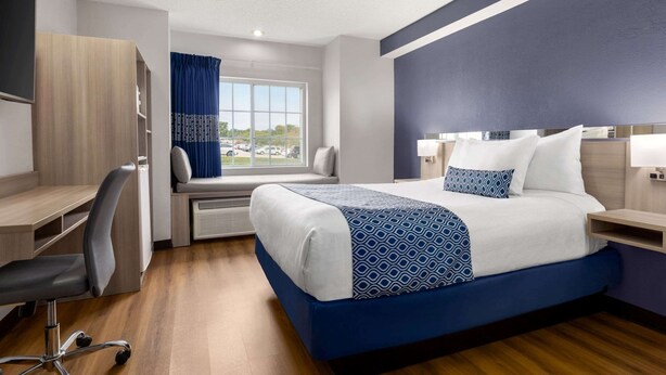 Une chambre d’hôtel équipée d’un lit, d’un bureau, d’une chaise et offrant une vue sur l’extérieur.