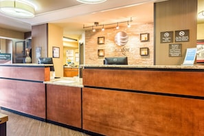 Zona de recepción de hotel con un mostrador de madera, una computadora y un cartel que indica que el hotel es 100% libre de humo.