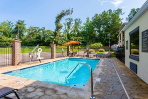 A swimming pool with a metal ladder, surrounded by a brick wall and stone tiles. - Comfort Inn Tupelo Central (Tupelo)