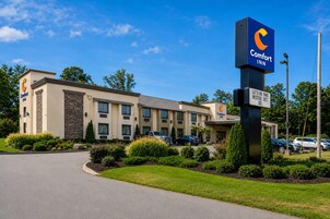 Un hotel Comfort Inn con un diseño moderno, que destaca un letrero azul con el logotipo de la marca.