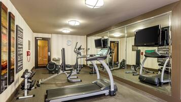 A hotel gym with treadmills, exercise bikes, and weights.