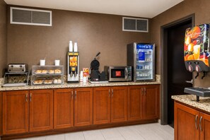 A hotel kitchen with a self-service breakfast station including a toaster, waffle maker, and coffee machine. - Comfort Inn Tupelo Central (Tupelo)