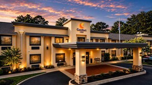A Comfort Inn hotel with a covered entrance, outdoor seating, and a landscaped area.