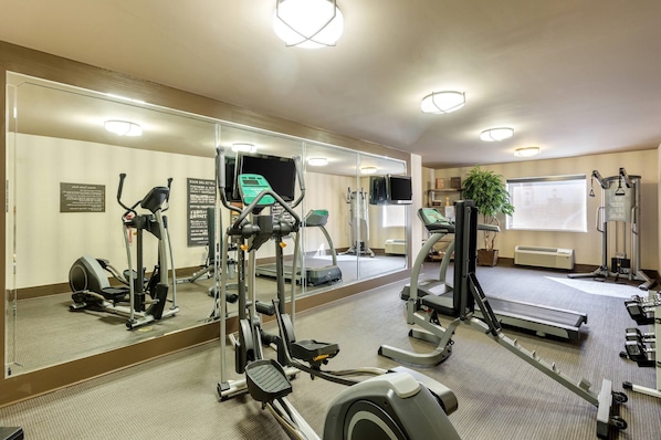 A gym with treadmills, elliptical machines, and free weights.