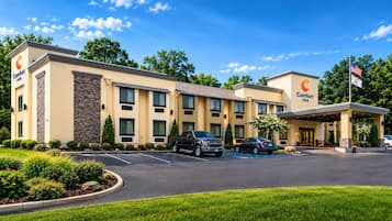 A Comfort Inn hotel with a parking lot, a flag, and a clear sky.