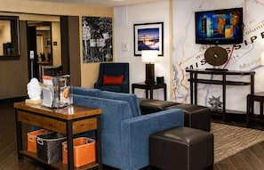 A hotel room with a sofa, armchair, table, lamp, TV, and a map on the wall. - Comfort Inn Tupelo Central (Tupelo)
