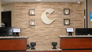 A reception desk with a large 'C' logo, two 'WELCOME!' signs, and a stone wall backdrop. - Comfort Inn Tupelo Central (Tupelo)